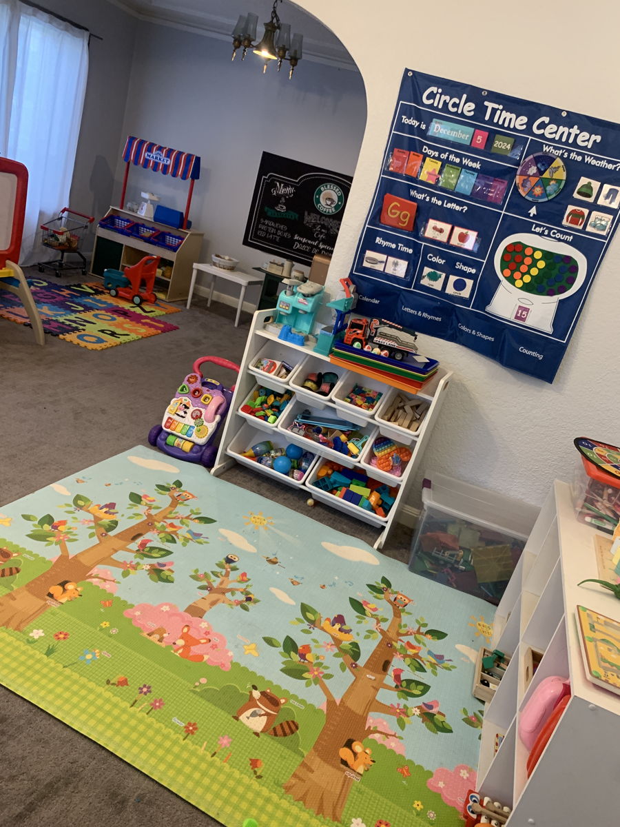 Indoor play area with a circle-time center, low shelves, and a soft rug