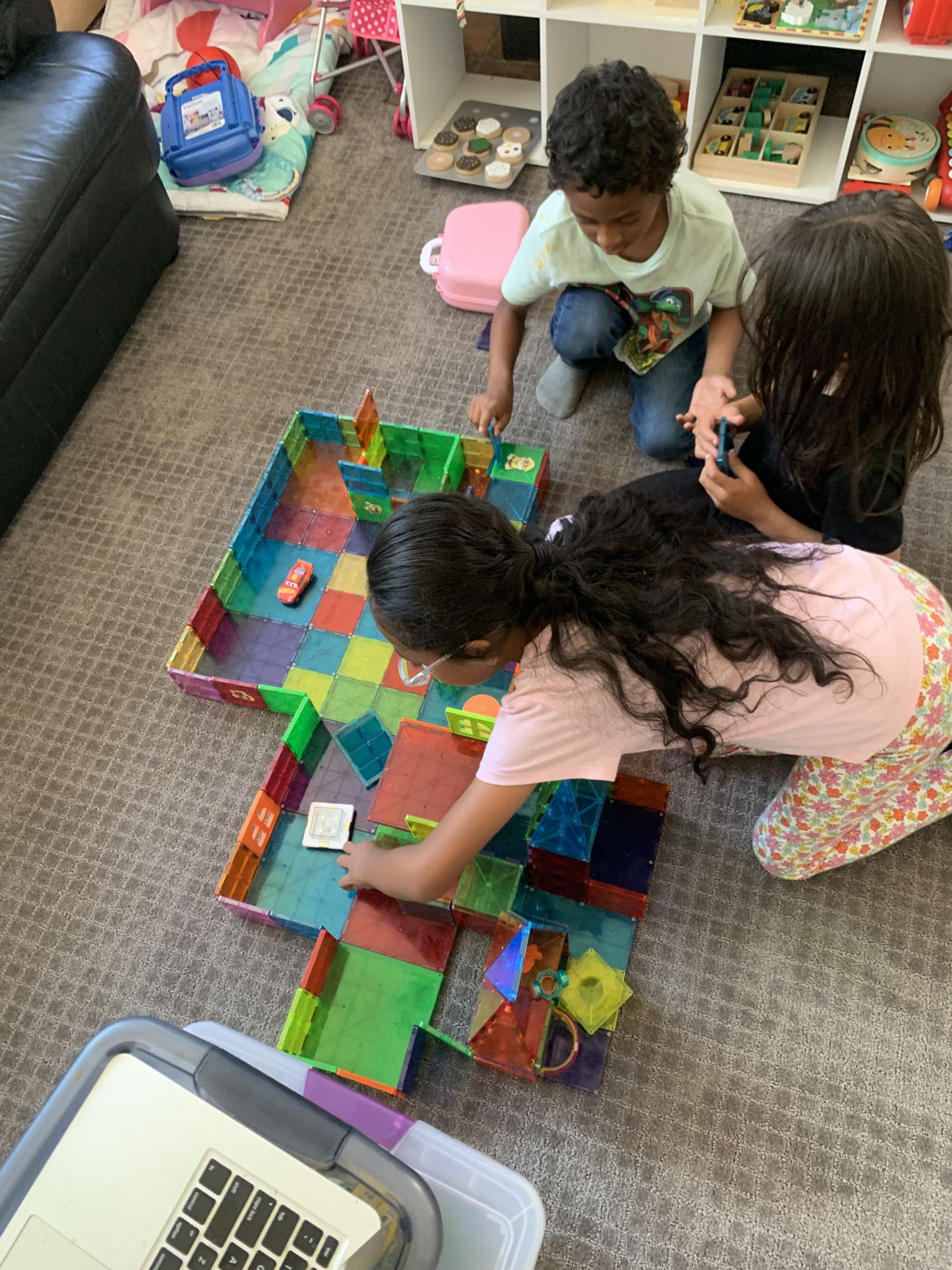 Children building with colorful magnetic tiles on the floor