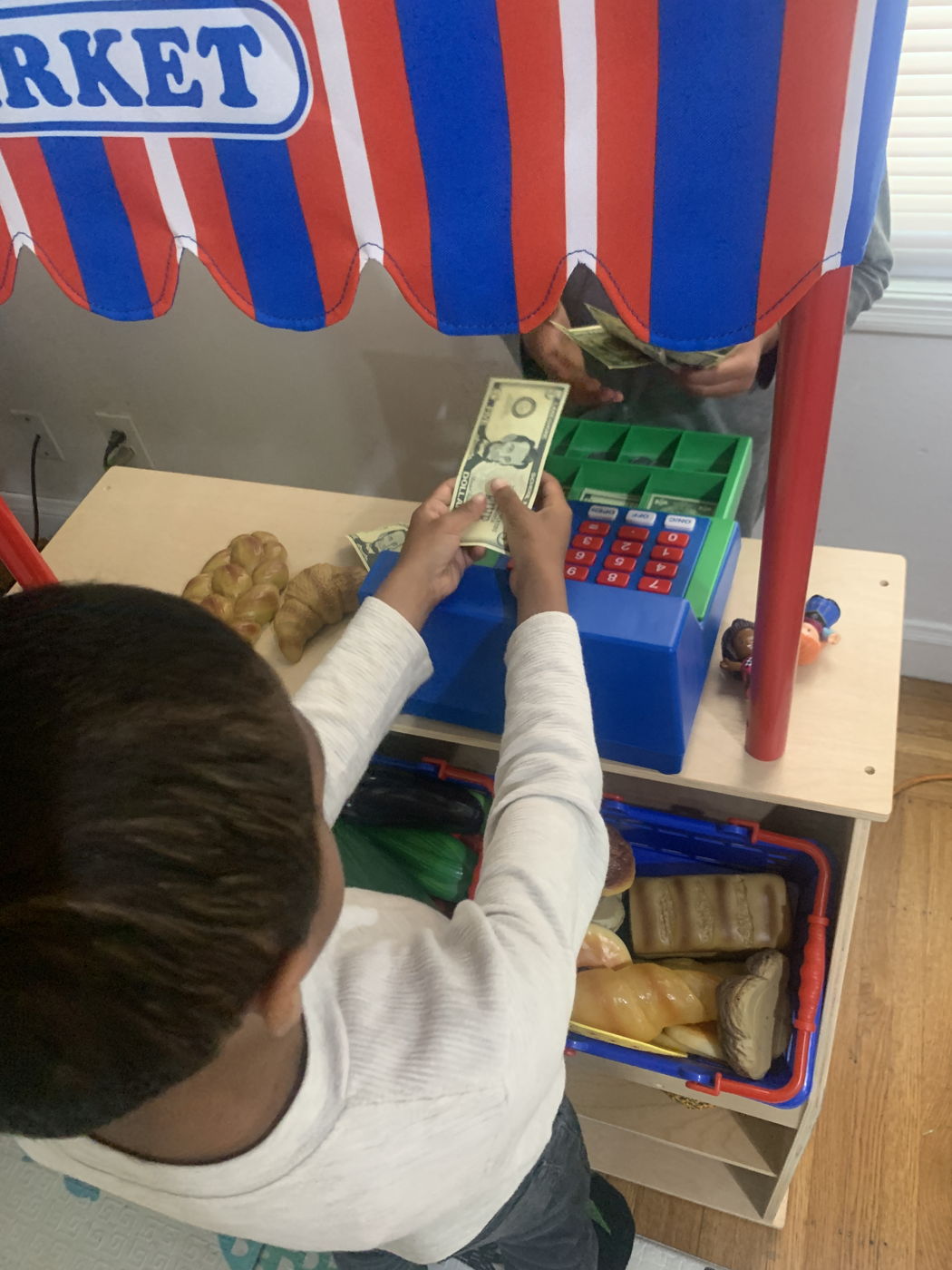 A child playing shopkeeper at a pretend market stand